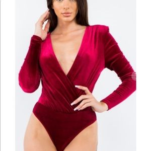 Red velvet like bodysuit with deep v neck, long sleeves and shoulder pads